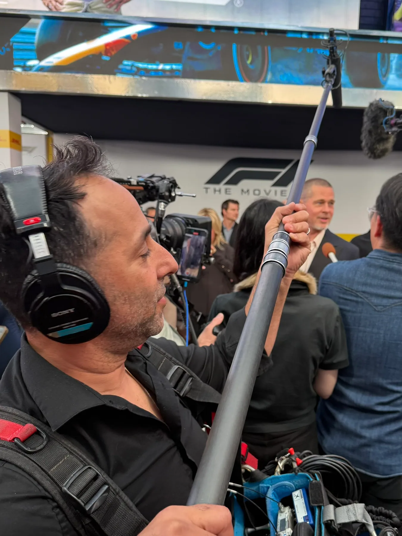 Matthew Legreca holding a boom microphone in a crowded press line